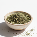 Dried basil herb in bowl on white background