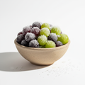 Frozen grapes in bowl on white background