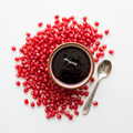 Pomegranate molasses in bowl with pomegranate seeds on white background